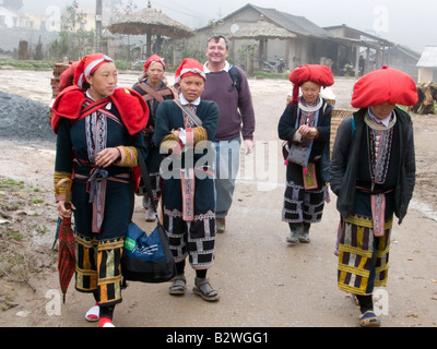 Red Dzao hilltribe donne clamore intorno i turisti e i bus turistici a vendere artigianato Ta Phin villaggio nei pressi di Sapa Vietnam Foto Stock