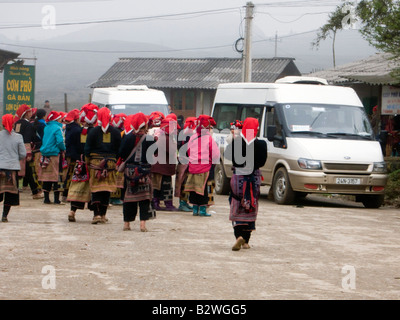 Red Dzao hilltribe donne clamore intorno i turisti e i bus turistici a vendere artigianato Ta Phin villaggio nei pressi di Sapa Vietnam Foto Stock