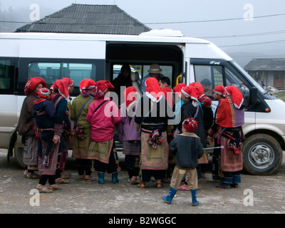 Red Dzao hilltribe donne clamore intorno i turisti e i bus turistici a vendere artigianato Ta Phin villaggio nei pressi di Sapa Vietnam Foto Stock