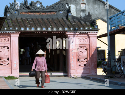 Cappello conico donna cammina dal caratteristico ponte coperto giapponese Hoi An Vietnam Foto Stock