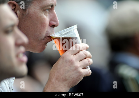 L'uomo sorsegge una pinta di birra mentre osserva il cricket nel pittoresco campo di Arundel Foto Stock