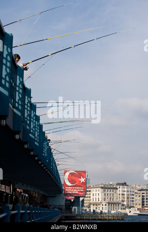 Il Ponte di Galata verticale di pesca. Una fila di coloratissimi canne da pesca pendere dal lato del Ponte di Galata, linee glinting Foto Stock