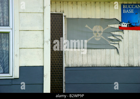 Un pirata bandiera su una casa in remoto il piccolo borgo di pescatori di Jackson, baia sulla costa occidentale dell'Isola Sud, Nuova Zelanda Foto Stock