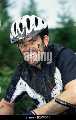 Uomo seduto all'aperto sulla bicicletta sporco e sorridente (messa a fuoco selettiva) Foto Stock