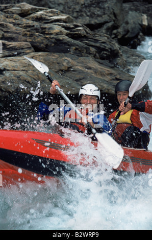 Due kayakers canottaggio in rapids e sorridente Foto Stock