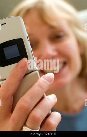 Un attraente bionda di mezza età della donna a parlare su un telefono cellulare. Girato con la profondità di campo minima. Focus è sul telefono. Foto Stock