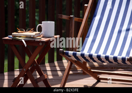 Una sedia in estate su un ponte al mattino con caffè e libri Foto Stock