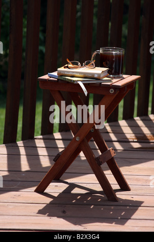 Un tavolo di legno su un ponte al mattino con caffè e libri Foto Stock