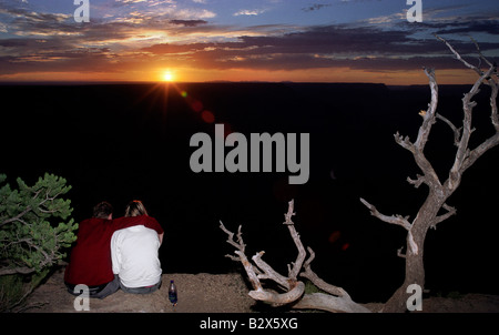 Un uomo e una donna si siedono sul bordo del Grand Canyon al tramonto nel Parco Nazionale del Grand Canyon Arizona Foto Stock