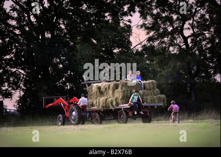 Una famiglia contadina raccolta di fieno in stile tradizionale nel GLOUCESTERSHIRE REGNO UNITO Foto Stock