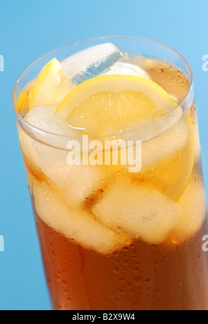 Vetro a freddo al limone tè ghiacciato con ghiaccio e limone su sfondo blu Foto Stock