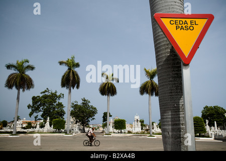 Un uomo che cavalca la sua bicicletta attraverso la necropoli Cristobal Colon nel cimitero di Havana, Cuba Foto Stock