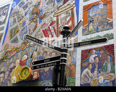 Cartelli stradali che indicano le attrazioni turistiche e il grande murale sulla parete off Carnaby Street, Londra Foto Stock