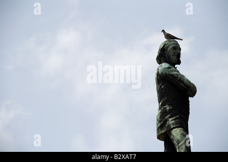 Un uccello si appoggia sulla testa di una statua presso la necropoli Cristobal Colon nel cimitero di Havana, Cuba Foto Stock