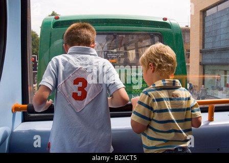 Due ragazzi sul piano superiore del double decker bus guardando fuori della finestra Foto Stock