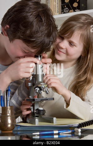 Due teenager lavorare i ragazzi con un microscopio - torna a scuola Foto Stock