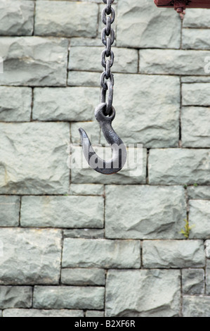 Un grande gancio di metallo su una spessa catena pendenti davanti un muro di ardesia Foto Stock