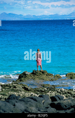 Donna all'aperto in piedi su grandi rocce Oceanside Foto Stock