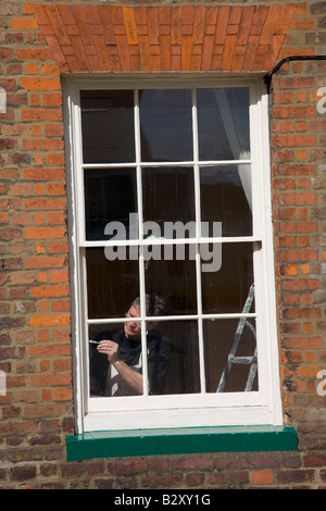 Pittore pittura all'interno di una vecchia finestra ad anta Foto Stock