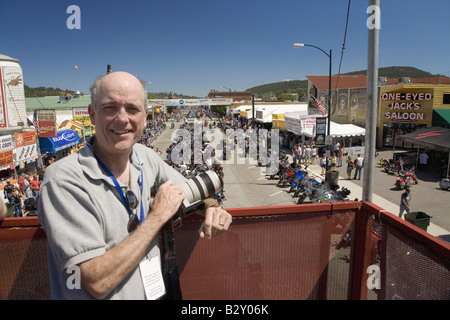 Fotografo Joe Sohm in posa sulla strada principale con panoramica della sessantasettesima Sturgis annuale Raduno motociclistico, SD Foto Stock