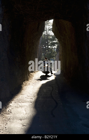 Motociclista guidando attraverso il tunnel su aghi autostrada, Black Hills, nei pressi del Monte Rushmore National Memorial, il Dakota del Sud Foto Stock