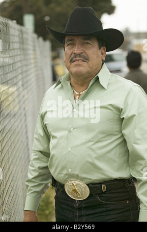 Un uomo ispanico in una camicia verde con un grande western cintura e cappello da cowboy in Oxnard in California Foto Stock