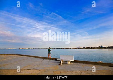 Fisherman e cane, la mattina presto sul Quay, Le Grau de roi, Languedoc-Roussillon, Francia Foto Stock