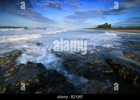 Bamburgh Beach con il castello di Bamburgh in background ad alta marea, Northumberland, Inghilterra Foto Stock