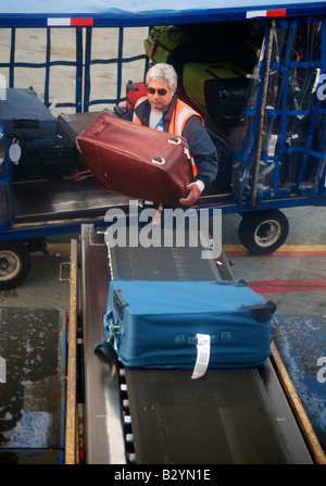 Un bagaglio carichi di gestore di una valigia su di un nastro trasportatore a Dallas Fort Worth International Airport in Texas, Stati Uniti Foto Stock