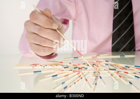 Imprenditore giocando Pick Up Sticks Foto Stock