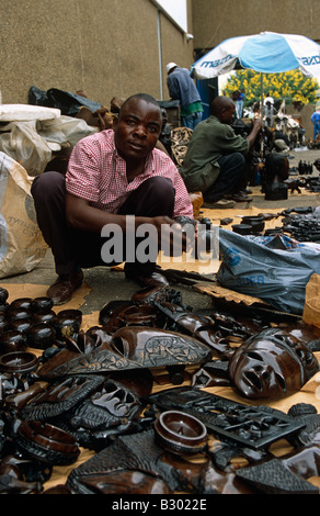 Titolare di stallo visualizzazione intagliato a mano le maschere in legno sul mercato in stallo, ritratto, Malawi, Africa Foto Stock