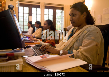 Un dipendente in Bangalore lavora sul suo computer in un ufficio di piccole dimensioni. Foto Stock