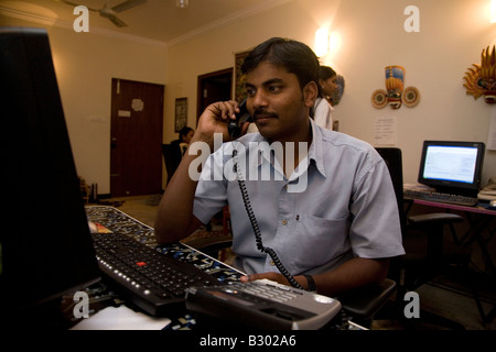 Un dipendente in Bangalore lavora sul suo computer in un ufficio di piccole dimensioni. Foto Stock