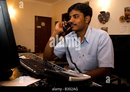 Un dipendente in Bangalore lavora sul suo computer in un ufficio di piccole dimensioni. Foto Stock