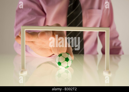 Imprenditore giocando con il calcio in miniatura Foto Stock