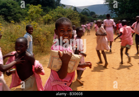 La folla di scolari lungo la pista sterrata in rosa di uniformi, Uganda, Africa Foto Stock