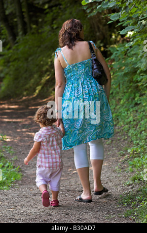 Madre e figlia 2 3 passeggiate in foresta mano nella mano vista posteriore Foto Stock