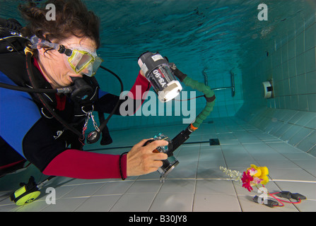 Donna scuba diver pratiche di fotografia subacquea in piscina Foto Stock