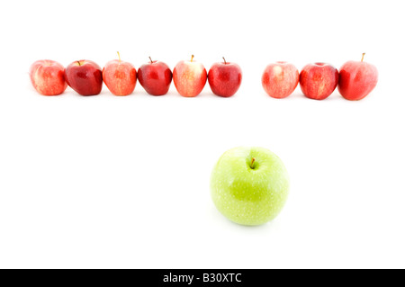 Una mela verde si distingue da una linea di mele rosse Foto Stock