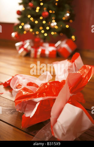 Utilizzata carta natalizia disposti su di un pavimento in legno nella parte anteriore di un albero di natale Foto Stock