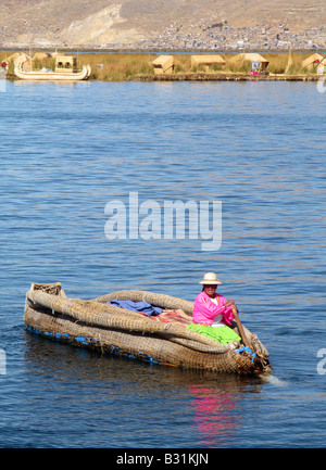 Un membro del popolo Uros remare una barca sul lago Titicaca, Perù, Sud America Foto Stock