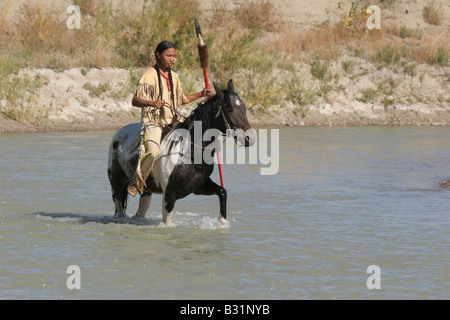 Un Nativo Americano indiano Sioux sul cavallo attraverso un ruscello in Sud Dakota Foto Stock