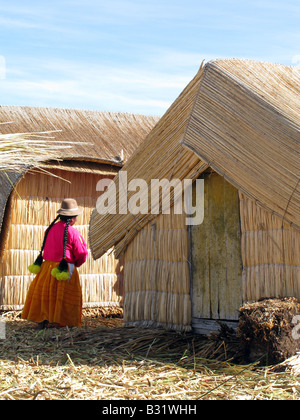 Un Uros donne vicino a capanne di reed on self-stile reed flottante isole del Lago Titicaca, Perù Foto Stock