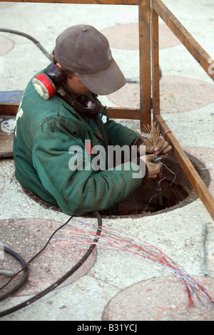 Un lavoratore di installare cavi, Odessa, Ucraina Foto Stock