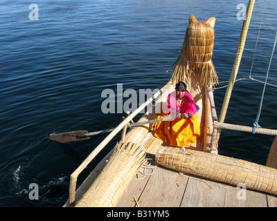 Un membro del popolo Uros remare una barca sul lago Titicaca, Perù, Sud America Foto Stock