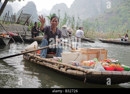 Una donna locale in canotto vendono spuntini e bevande analcoliche per i turisti sulle Ong Dong fiume in Tam Coc, nel Vietnam del nord. Foto Stock