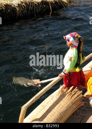 Una ragazza Uros gente un pre-Inca le persone che vivono sul self-stile reed flottante isole del Lago Titicaca, Perù Foto Stock