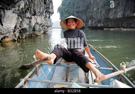 Una donna vietnamita canottaggio il boat con i suoi piedi sulle Ong Dong fiume in Tam Coc, nel Vietnam del nord. Foto Stock