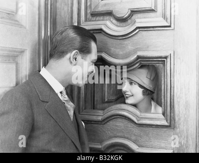 Paio di interagire attraverso il foro nella porta Foto Stock