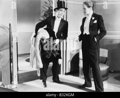 Due uomini in tuxedos con inconscio donna Foto Stock